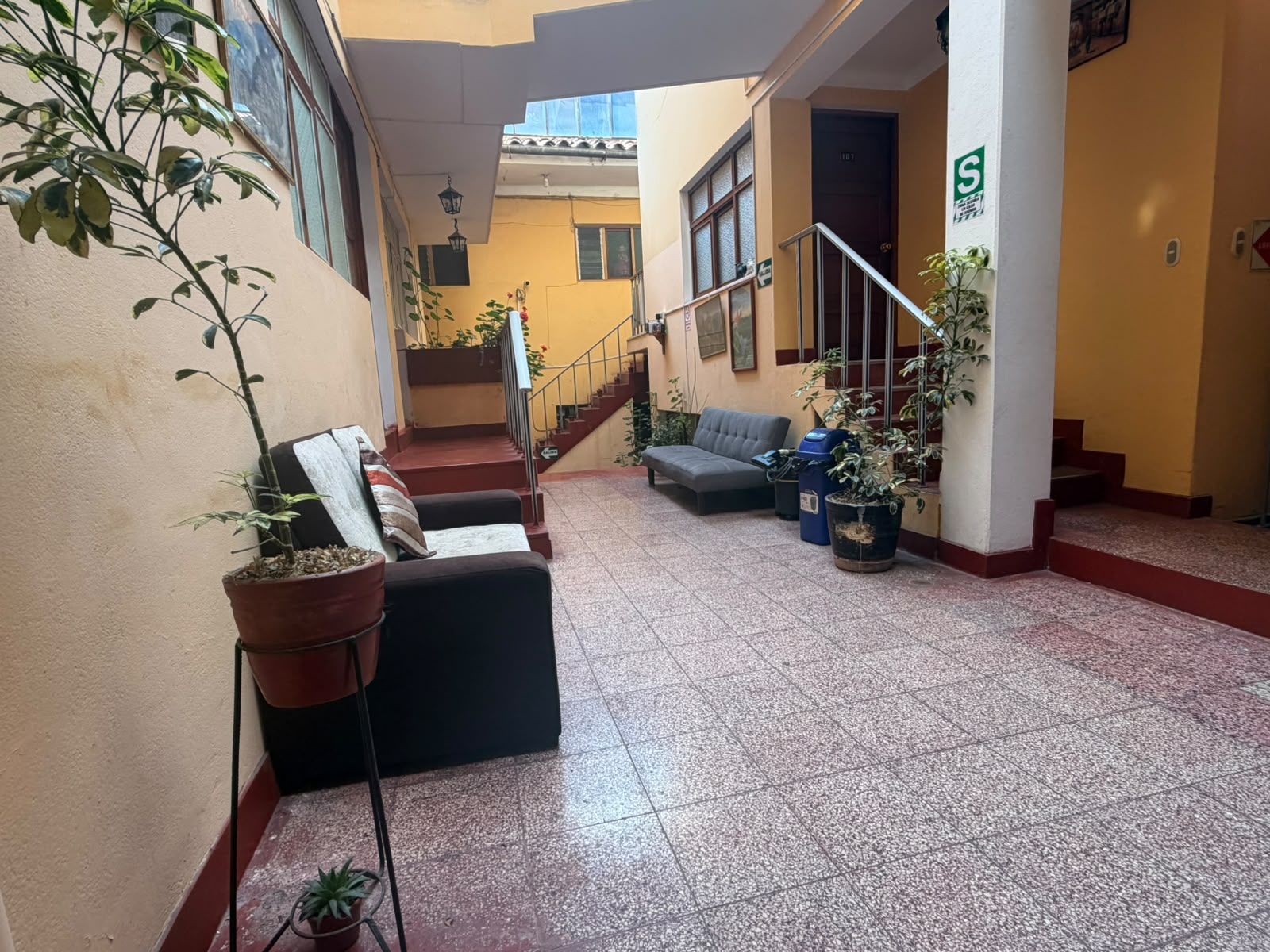 A hotel lobby with a staircase, seating area, and potted plants.