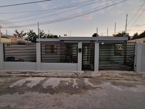 Uma entrada protegida por portão de metal e muro.