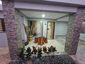Um interior moderno com uma mesa de madeira central, plantas em vasos e uma parede decorativa.