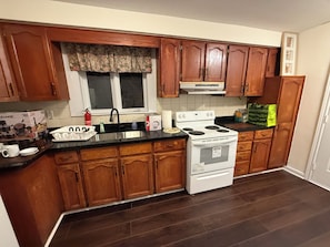 A kitchen with wooden cabinets, a white stove, and a black countertop. - Private room in good location (Toronto)