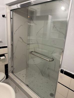 A glass-enclosed shower stall with a metal grab bar, a toilet, and a tiled floor. - Private room in good location (Toronto)