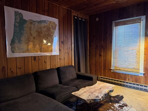 A room with a wooden ceiling, a large map on the wall, a sofa, a window with blinds, and a small table. - Comfortable and quirky updated 3-bedroom bungalow in peaceful Monroe (Monroe)