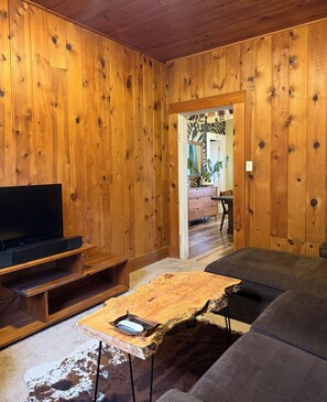Een kamer met houten lambrisering, een televisie, een leren bank en een salontafel.