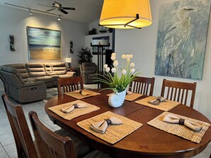 A dining area with a round table, chairs, placemats, and a vase with flowers. - 3 Bedroom Spacious AC Pool Home w/ Gameroom (Lakeland)