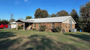 A single-story stone building with a metal roof, a covered porch, and a garage. - Pop’s Place at Blackgum - near Lake Tenkiller, sleeps 8-10, handicap accessible (Vian)