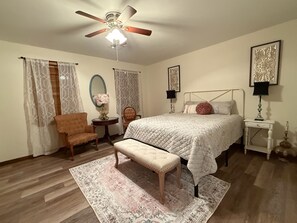 A bedroom with a bed, a chair, a bench, a nightstand, a lamp, a ceiling fan, and a rug. - Pop’s Place at Blackgum - near Lake Tenkiller, sleeps 8-10, handicap accessible (Vian)