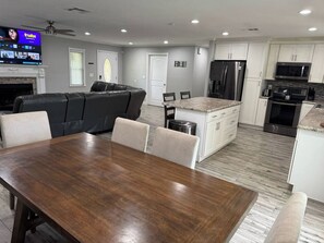 A modern kitchen with white cabinets, stainless steel appliances, and a wooden dining table with four chairs. - 4 Bedroom Cul-de-Sac Pool Home w/ Gameroom (Lakeland)