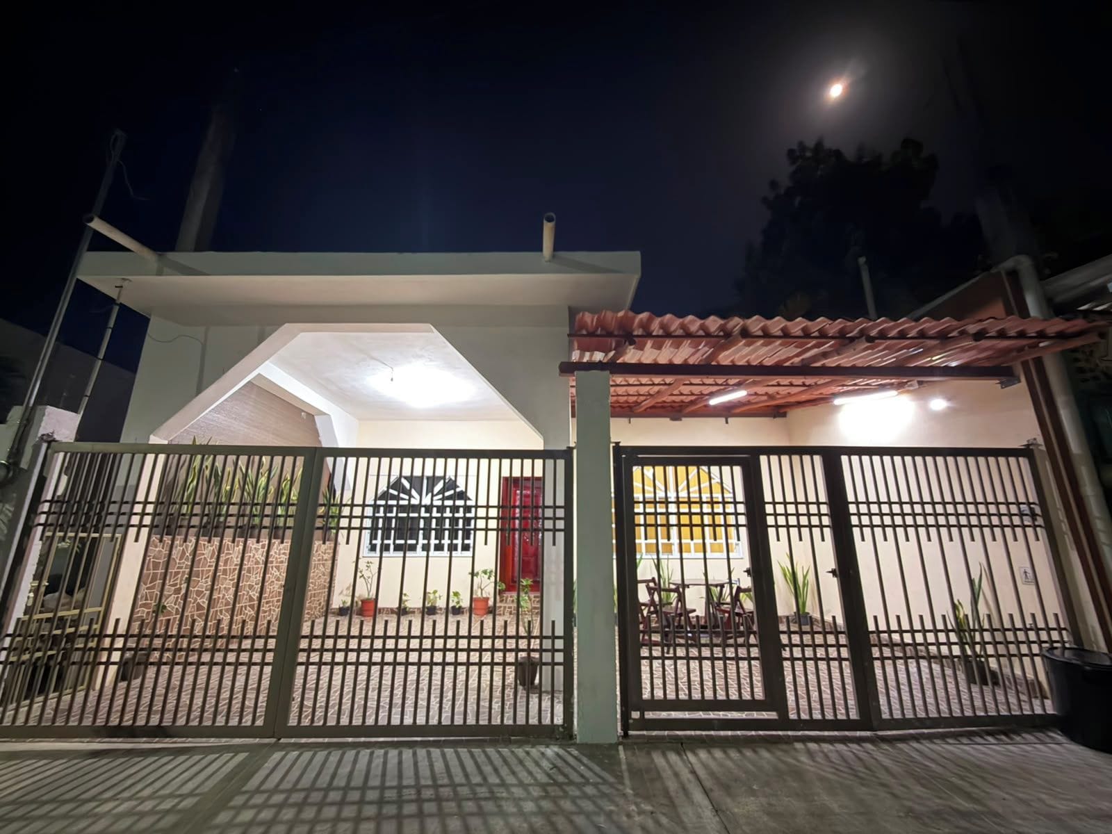 A gated entrance to a building with a covered patio area and a visible window.