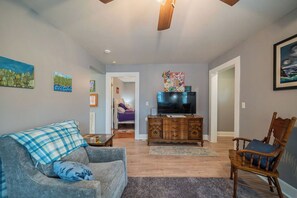 A living room with a sofa, a wooden cabinet, a television, and artwork on the walls. - The Rain Dancer Art House. (Paducah)