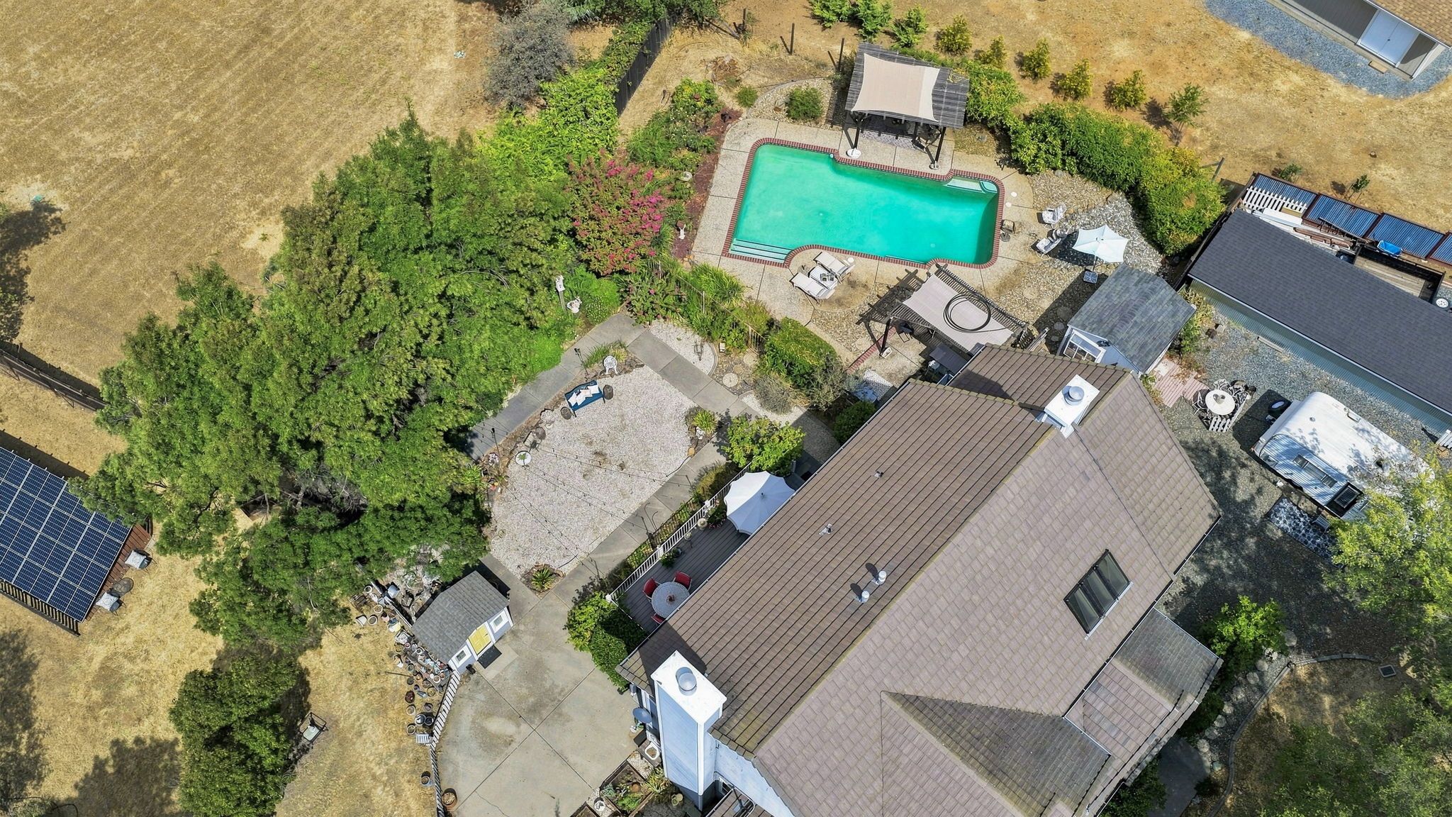 Ett bostadsområde med en swimmingpool, solpaneler och ett hus med ett sluttande tak.