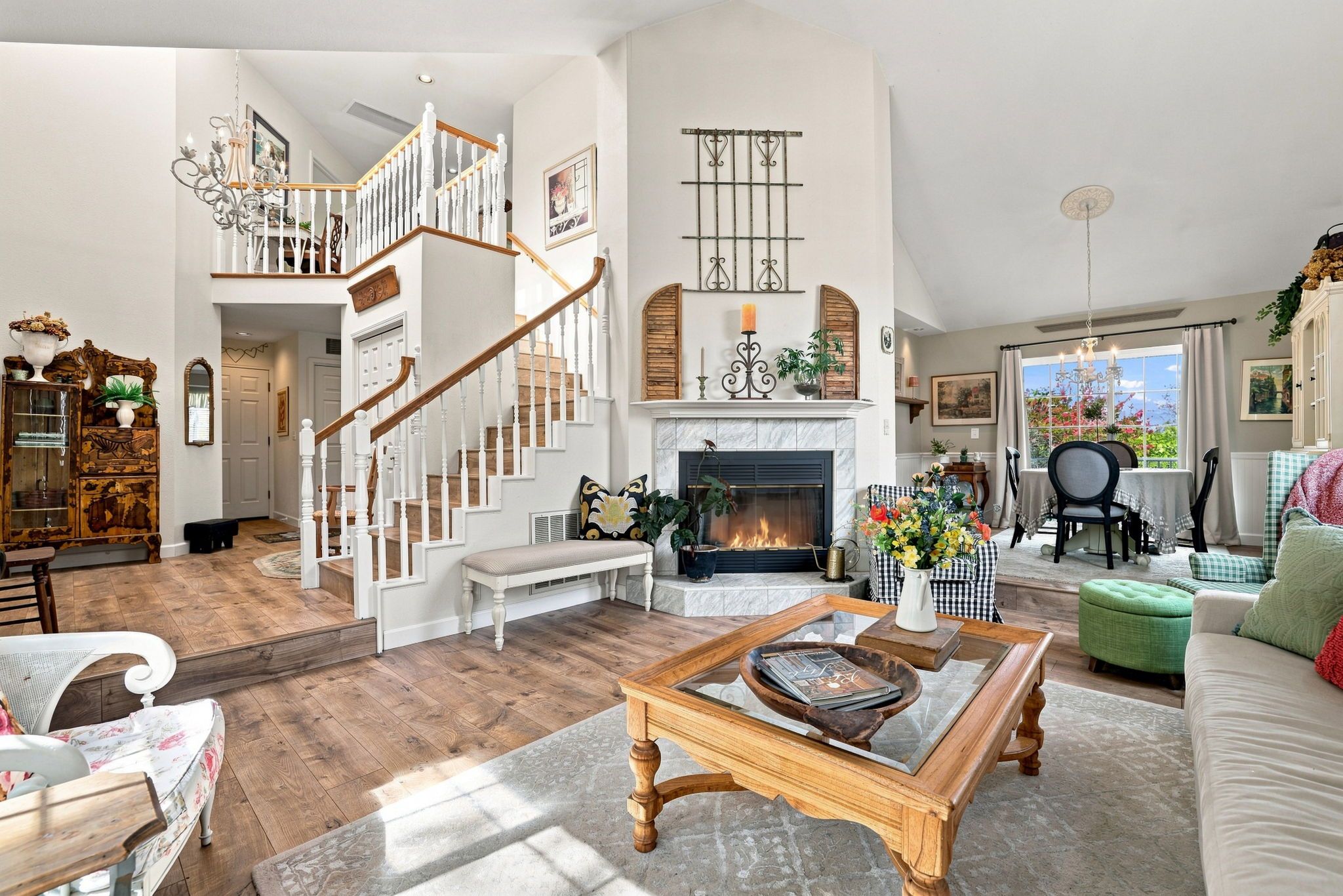 A spacious living room with a fireplace, a staircase, and a dining area with a view.