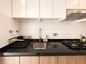 Eine Küche mit einem Edelstahlspülbecken, einem Gasherd und einer schwarzen Arbeitsplatte.