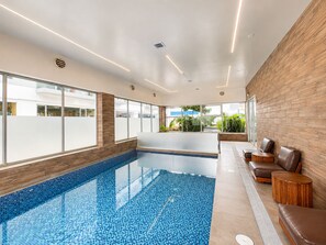 Ein moderner Innenpoolbereich mit einer Glaswand, einem Empfangstresen und einer Sitzecke.