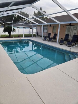 A swimming pool with a covered area, lounge chairs, and a ceiling fan. - 3 Bedroom Cul-de-Sac Pool Home (Lakeland)
