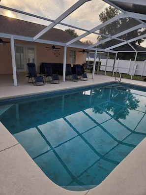 An indoor swimming pool with a clear view of the sky, surrounded by a covered patio area with chairs and a ceiling fan. - 3 Bedroom Cul-de-Sac Pool Home (Lakeland)