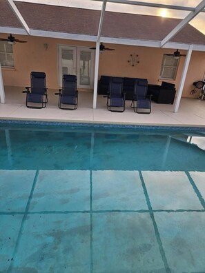 Une piscine avec des chaises longues et un espace patio couvert.
