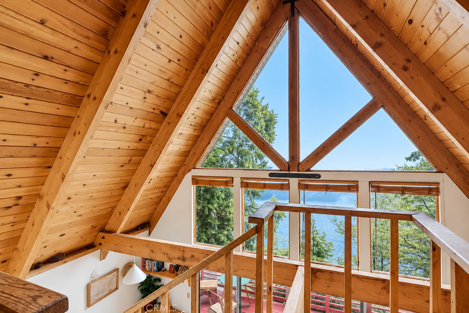 A wooden interior with a high ceiling and a view of a lake through large windows.