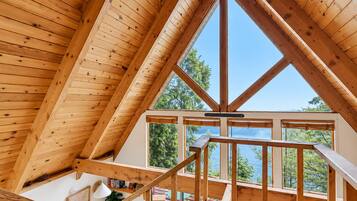 A wooden interior with a high ceiling and a view of a lake through large windows.