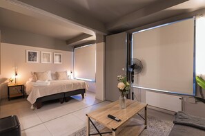 A modern bedroom with a bed, bedside tables, a wooden coffee table, and a large window. - Quiet Studio · Selected Design (H18) (Providencia)