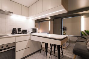 A modern kitchen with a central island, a microwave, a coffee maker, and a toaster. - Quiet Studio · Selected Design (H18) (Providencia)