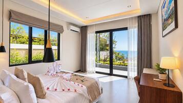 A modern hotel room with a large bed, a view of the sea, and a balcony.