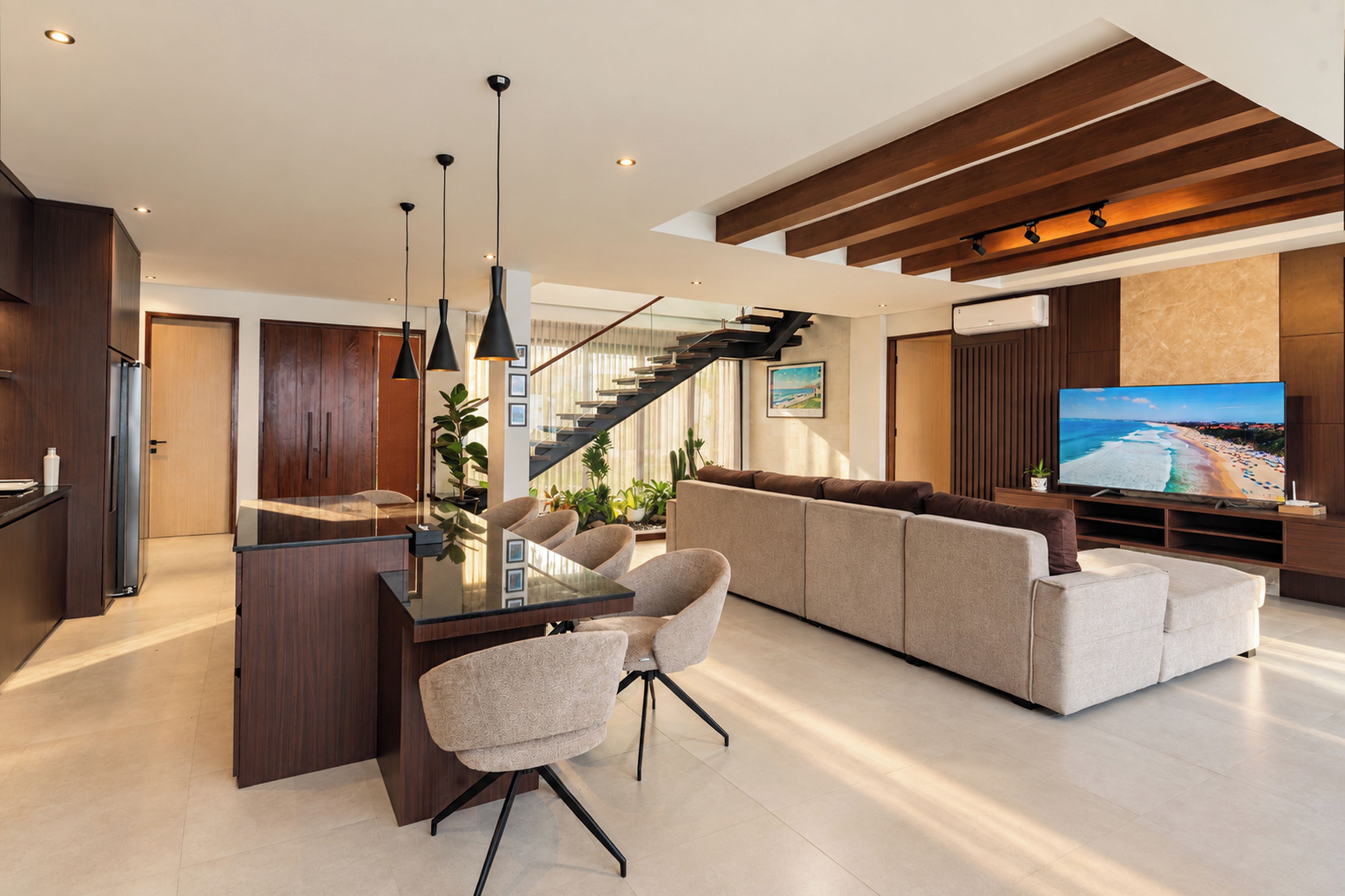 A modern living room with a glass dining table, sofas, and a large flat-screen TV.