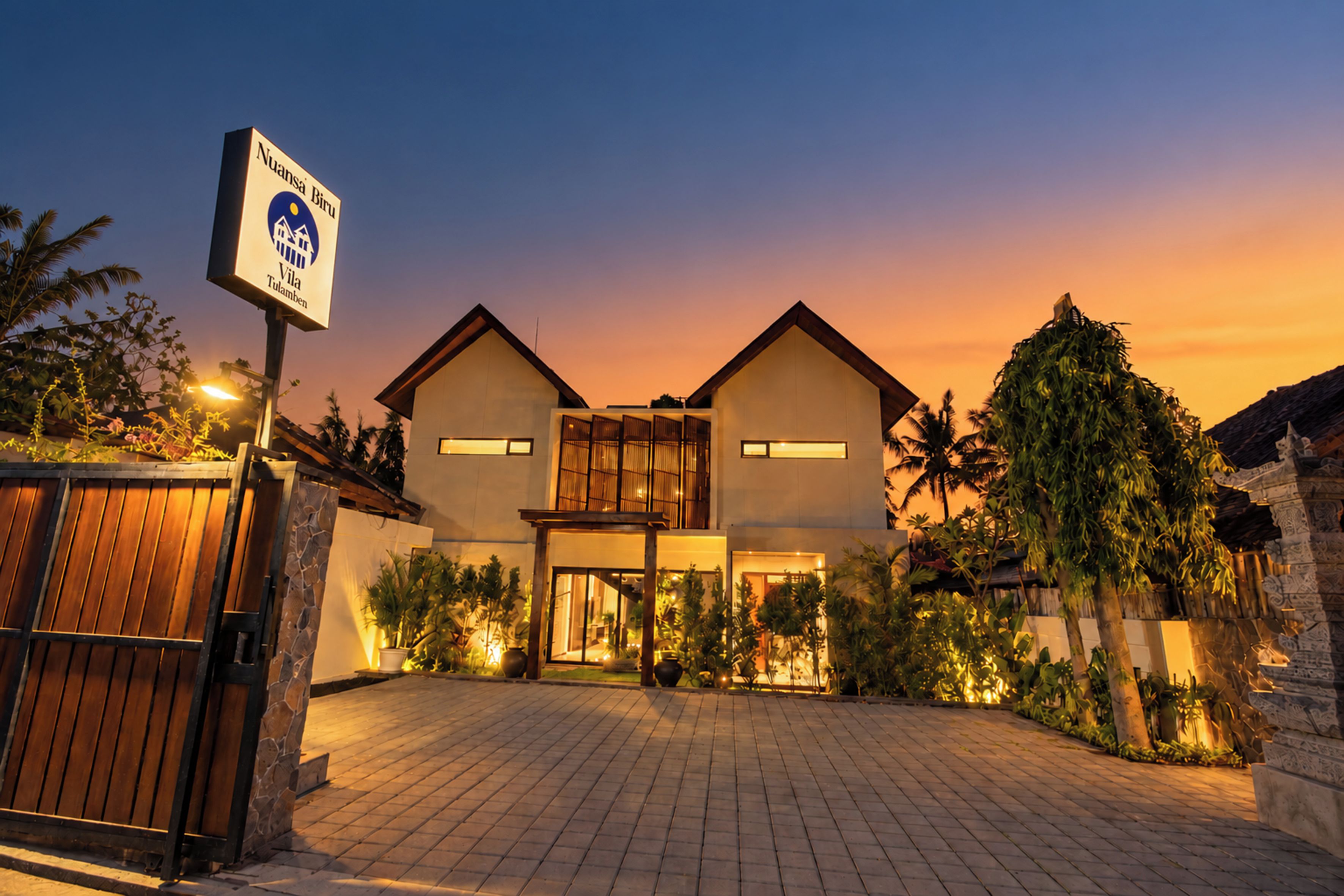 A hotel with a two-story structure, a gated entrance, and a signboard.