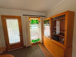 A hallway with a wooden door, a glass door with green floral patterns, and a wooden cabinet with glass doors. - Bluebird Habitat: A Marfa Home Away from Home (Marfa)