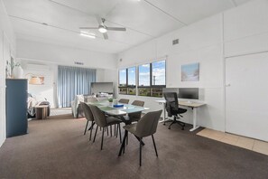 A conference room with a table, chairs, a computer, and a view of the outdoors. - Beach Shack Escape Beach Just Across the Road (Aldinga Beach)