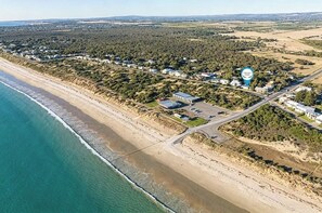 An aerial view of a coastal area with a beach, residential buildings, and a road network. - Beach Shack Escape Beach Just Across the Road (Aldinga Beach)