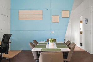 Une salle de conférence avec un mur d’accent bleu, une table blanche et des chaises marron.
