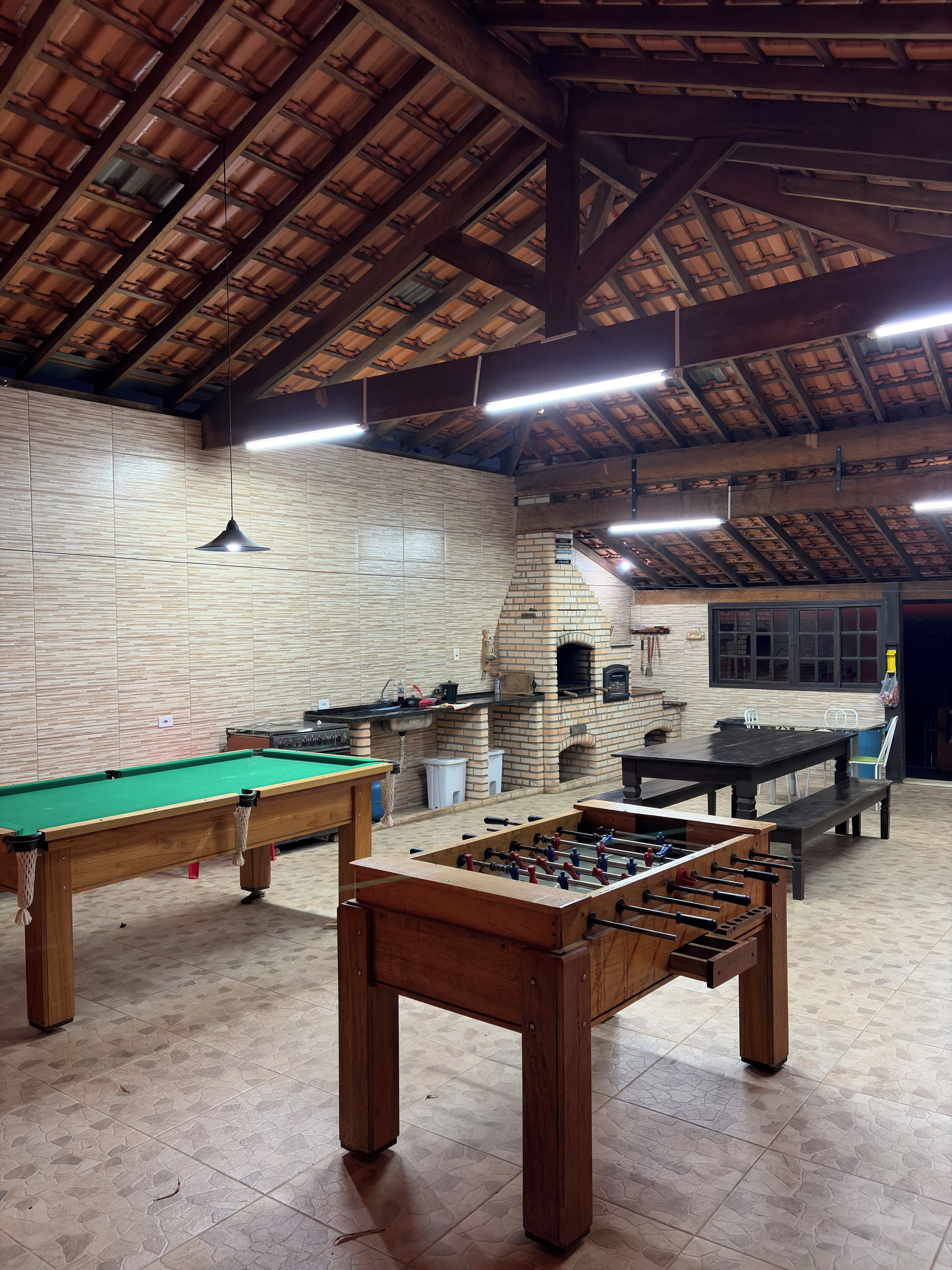 An indoor recreational area with a pool table, foosball table, and a brick oven.