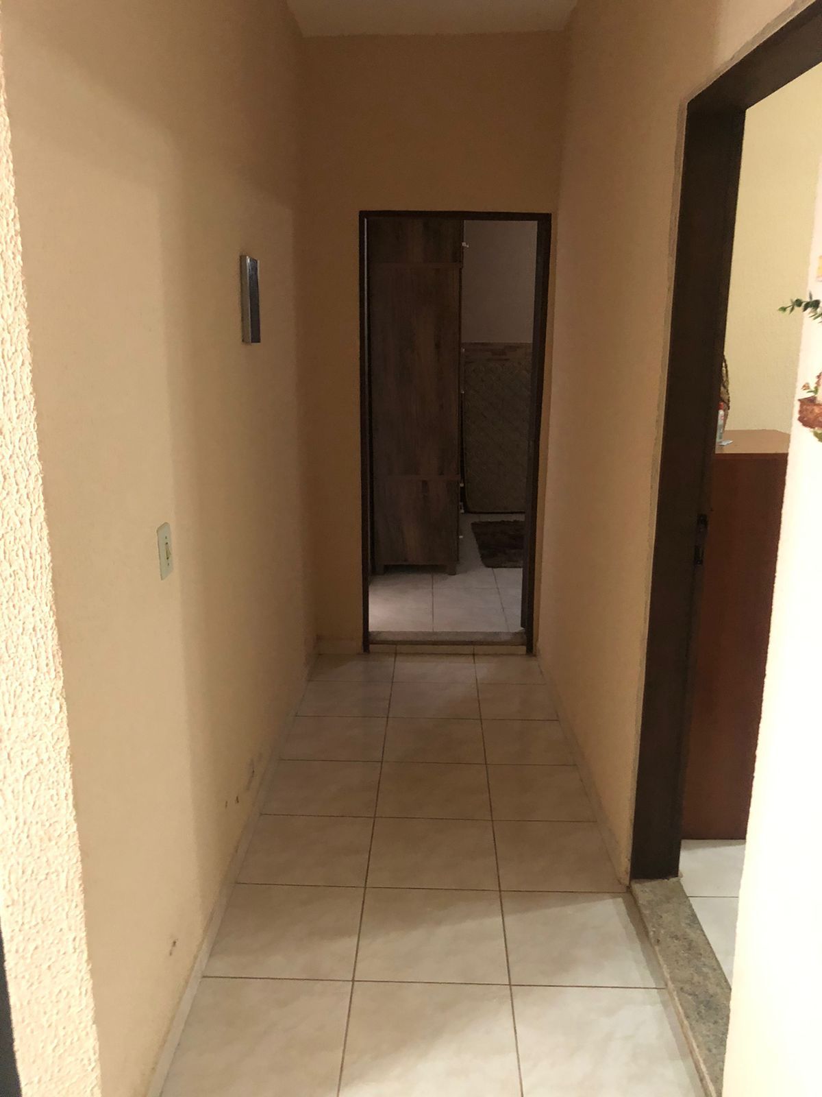 A narrow hallway with a tiled floor leading to a door.