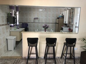 A compact kitchen with a central island, two bar stools, and a microwave.