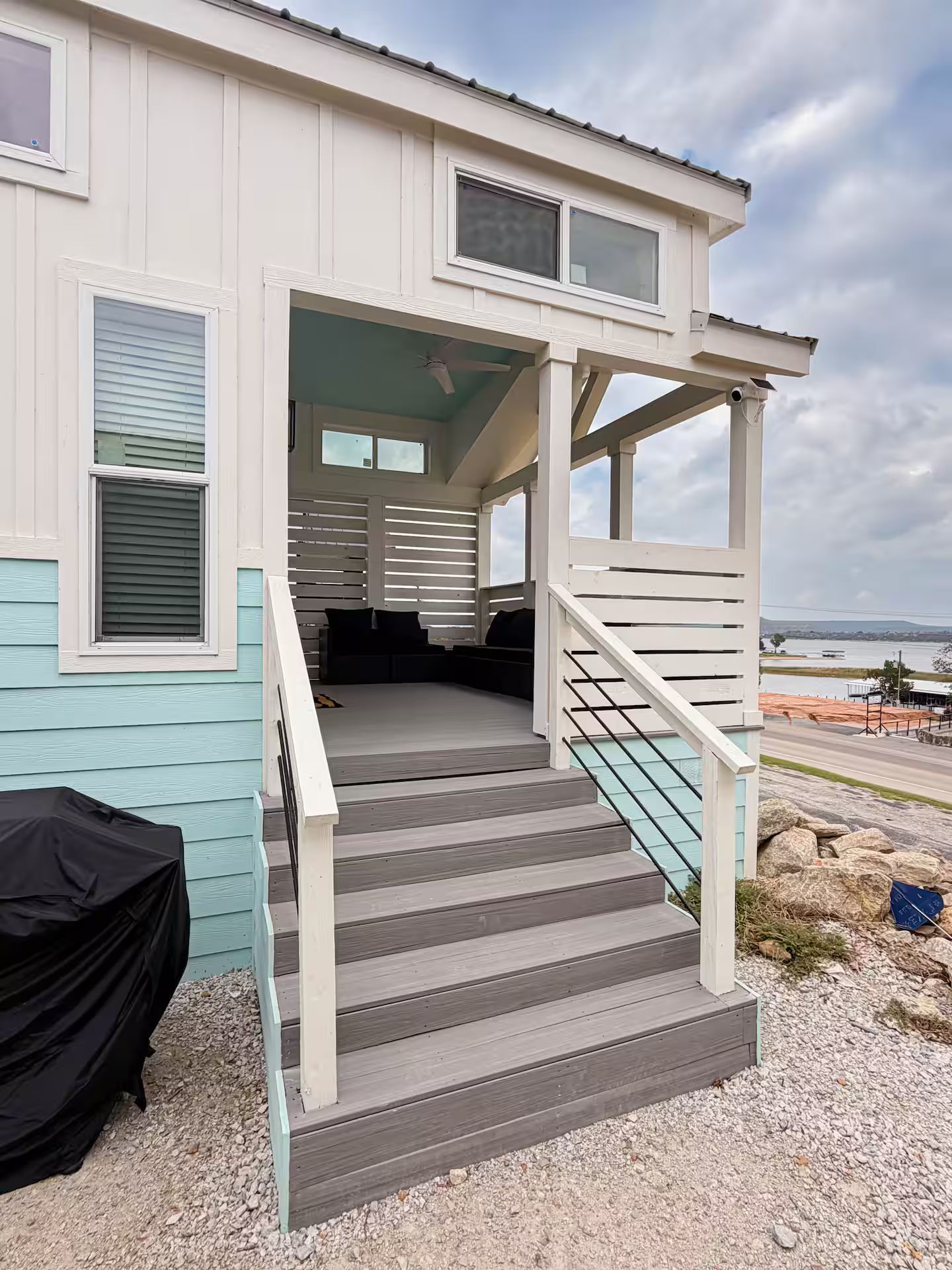 A two-story building with a covered porch, a staircase, and a view of the water.