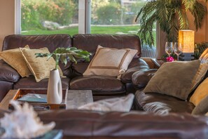 Ein braunes Ledersofa mit dekorativen Kissen und einer Vase mit grünen Blättern.