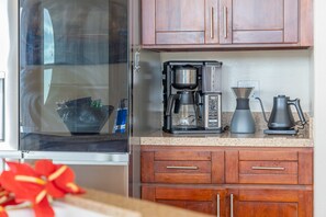 A kitchen with a coffee maker, a kettle, and a microwave. There is a window with a view of the outside. - Pool & Ocean View Villa: 3BD | Sunset Kona Side (Kailua-Kona)