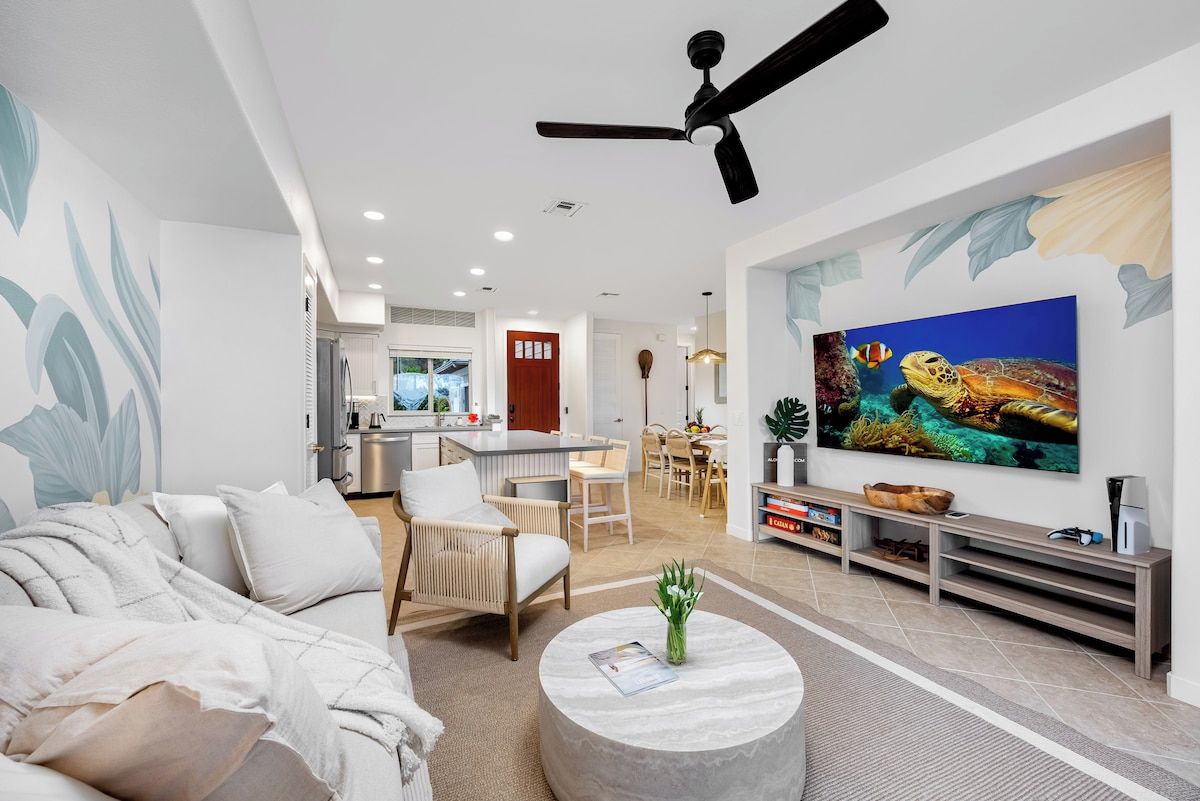 A modern living room with a sofa, chairs, a coffee table, and a TV.