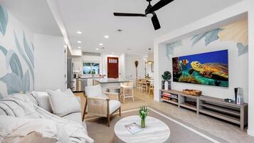 A modern living room with a sofa, chairs, a coffee table, and a TV.