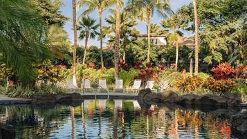 A pool area with lounge chairs and tropical vegetation.