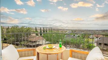 A balcony with a round wooden table, two chairs, and a bottle of water.