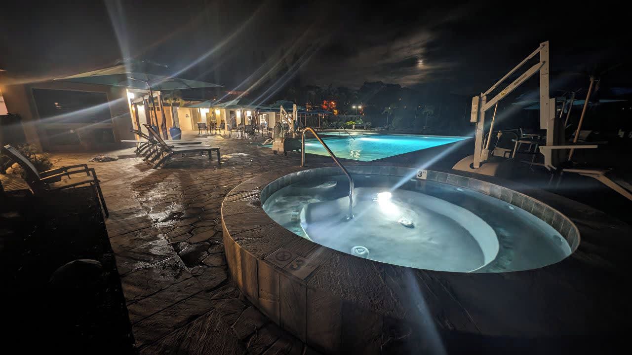 Un área de hidromasaje con piscina, rodeada de suelo de piedra y mobiliario de exterior.