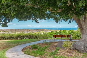 A park bench overlooking a coastal landscape with a clear view of the ocean and distant hills. - Upgraded 3 bed w Ocean View, Pool, Hot tub, 2 King (Waikoloa Village)