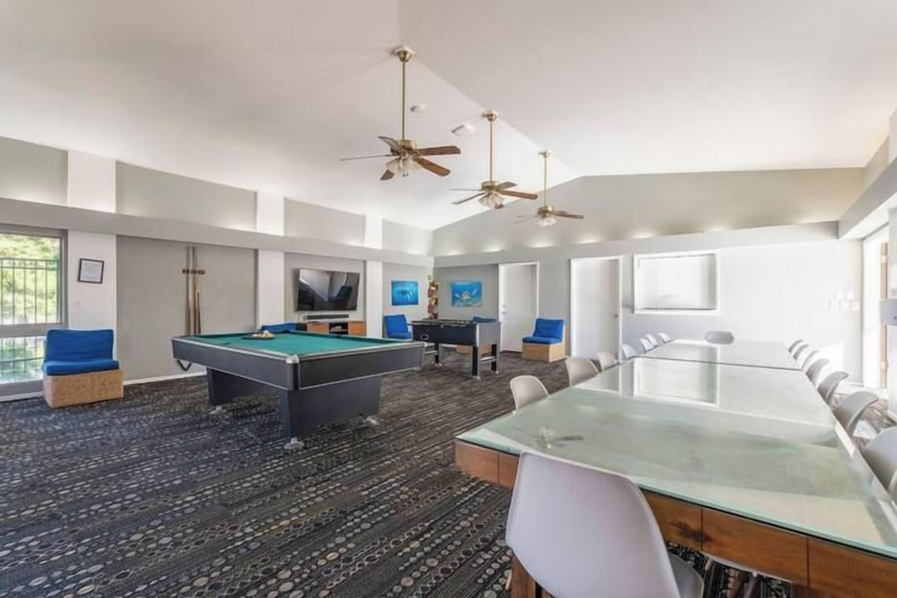A modern indoor space with a pool table, a long dining table, and a conference table.