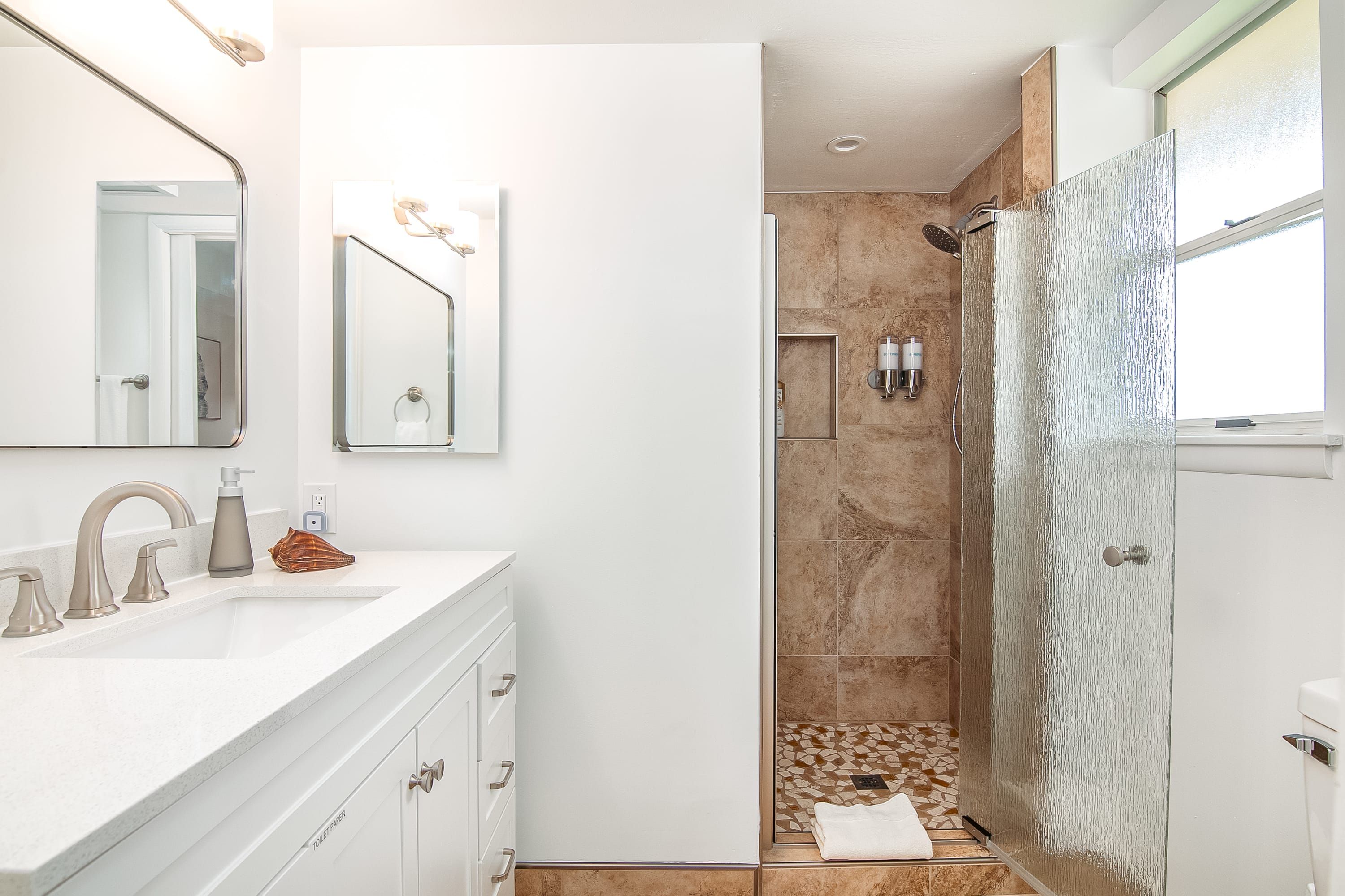 A modern bathroom with a white vanity, a large mirror, and a shower area with a glass door.