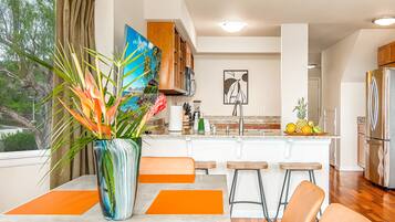 A modern kitchen with a central island, bar stools, and a large window with curtains.