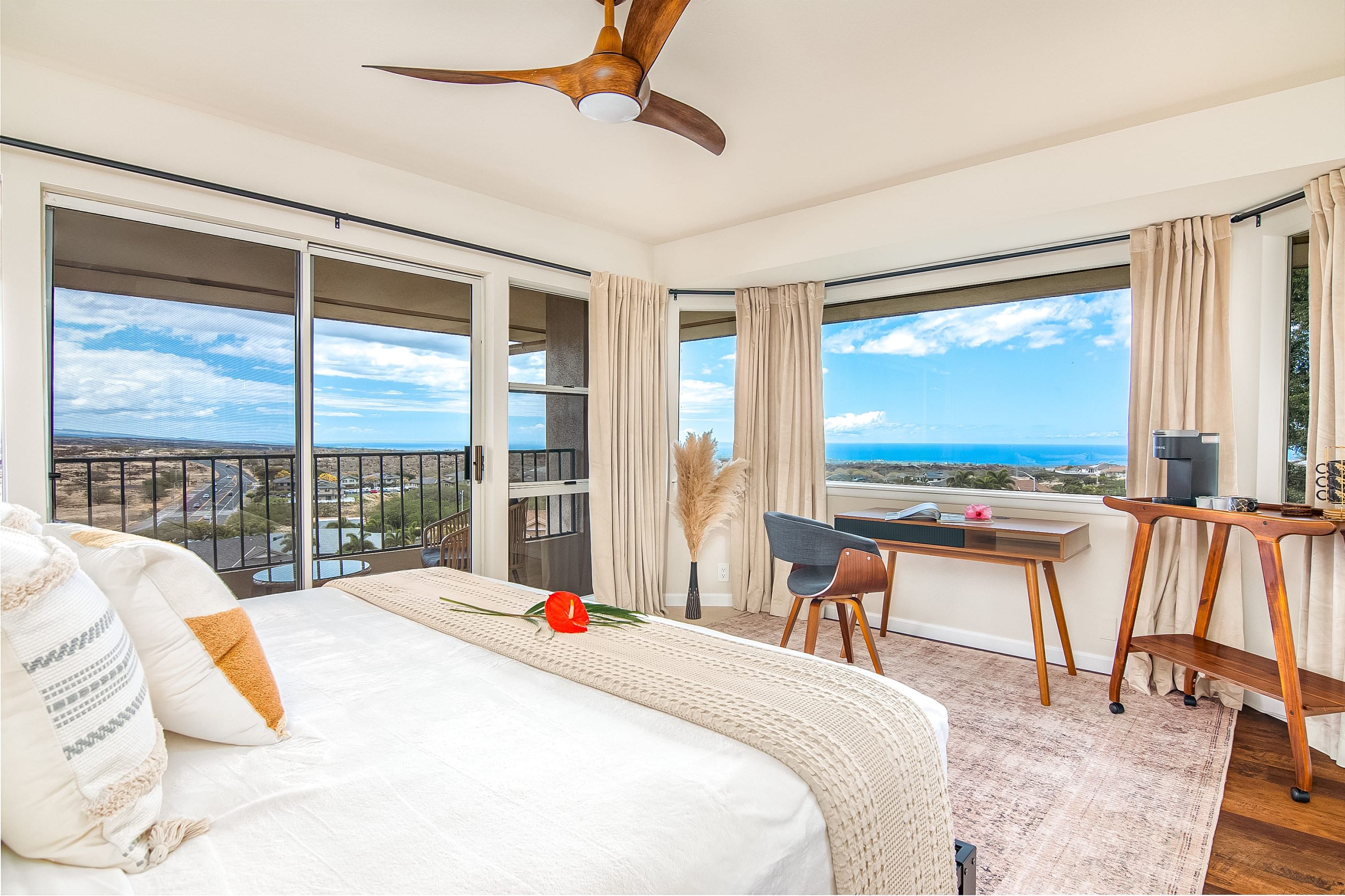 A hotel room with a large bed, a desk, and a view of the ocean.