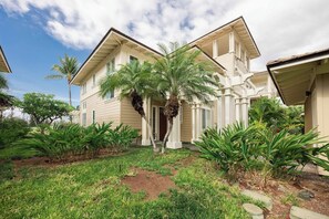 A two-story house with a front porch, palm trees, and a well-maintained lawn. - Treasure Retreat 3 bed Villa, Kings, Stylish Remodel (Waikoloa Village)
