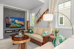 A living room with a flat-screen TV, a wooden coffee table, a sofa, and a lamp. - Treasure Retreat 3 bed Villa, Kings, Stylish Remodel (Waikoloa Village)