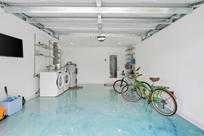 A clean, spacious garage with a washing machine, a bicycle, and a flat-screen TV mounted on the wall. -  Naples Beach 3BR Home with Amazing Pool,Hot Tub,garage,2 MI to the Beach (Naples)